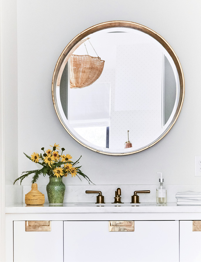 Brass in the bath pops against soft gray walls painted in Farrow &amp; Ball’s “Slipper Satin.”