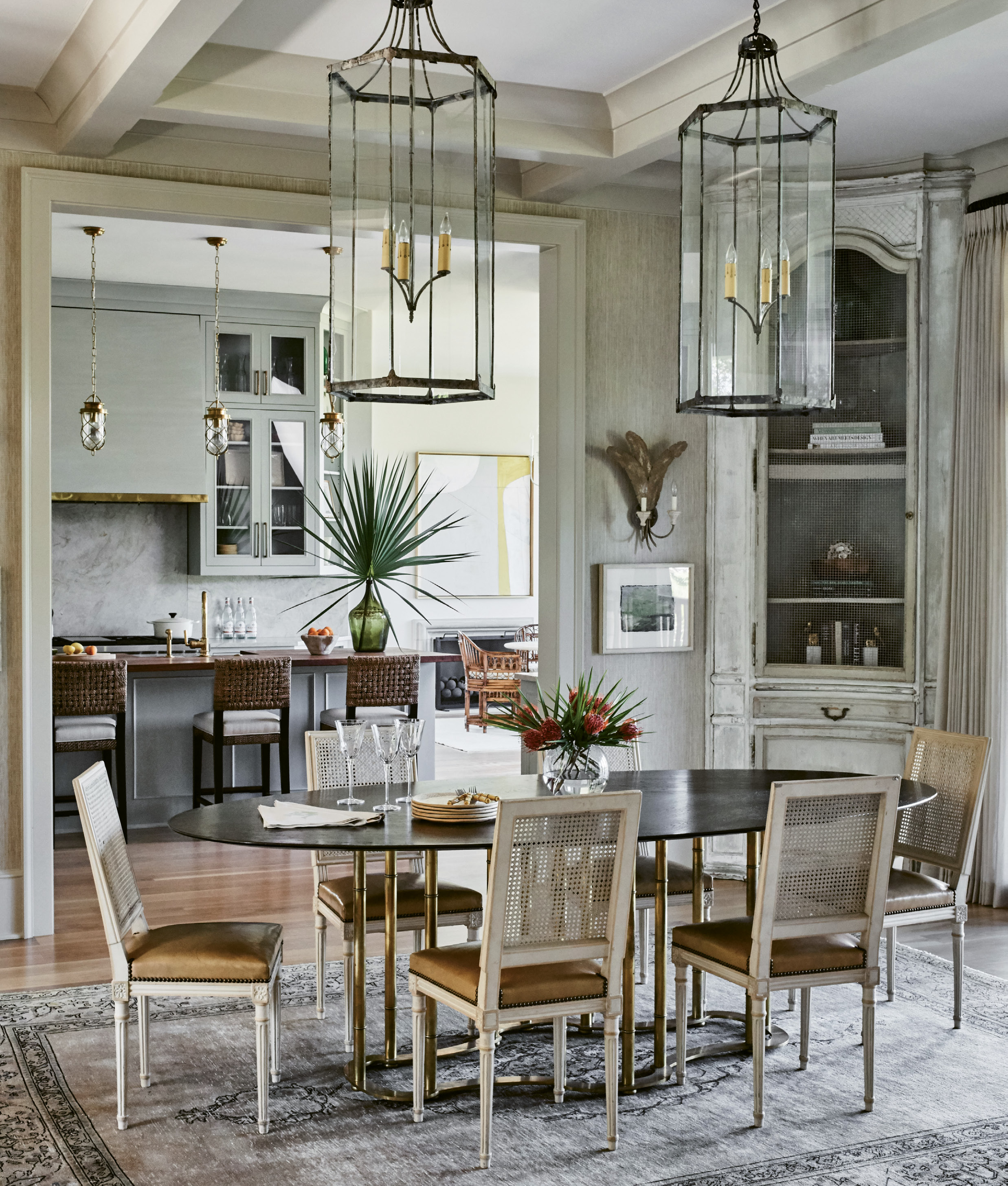 FINE DINING: Custom-engineered antique corner cabinets from Alexandra AD anchor the open-plan dining room that’s further defined by an Oushack rug. Illuminating the scene are antique pendant lanterns, also from Alexandra AD. “We didn’t want a lot of canned light, so we used as much accent lighting and as many fixtures as possible, blending older with newer pieces,” notes Lucas.
