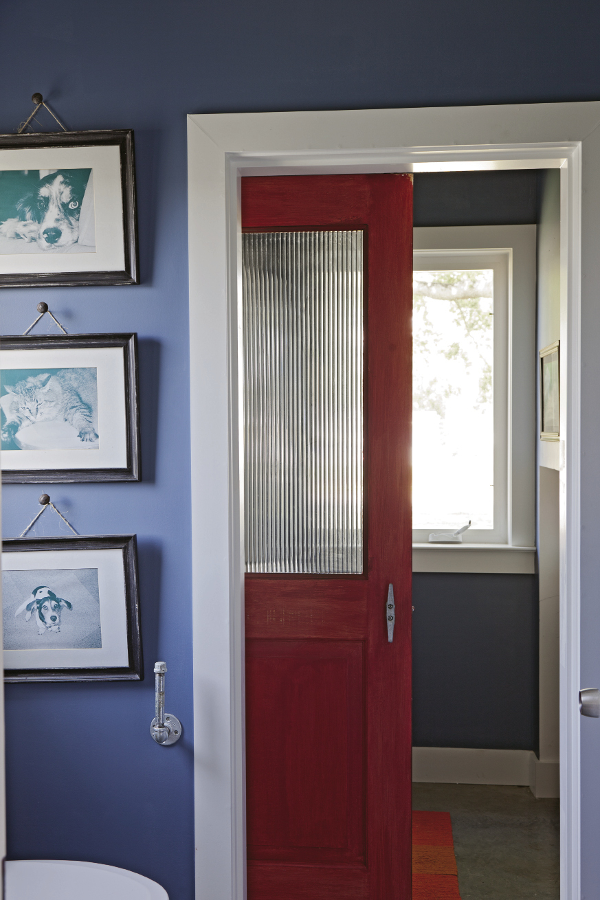 Mathis installed a door found at The Sustainable Warehouse in the first-floor bath, where it keeps the laundry room out of view.