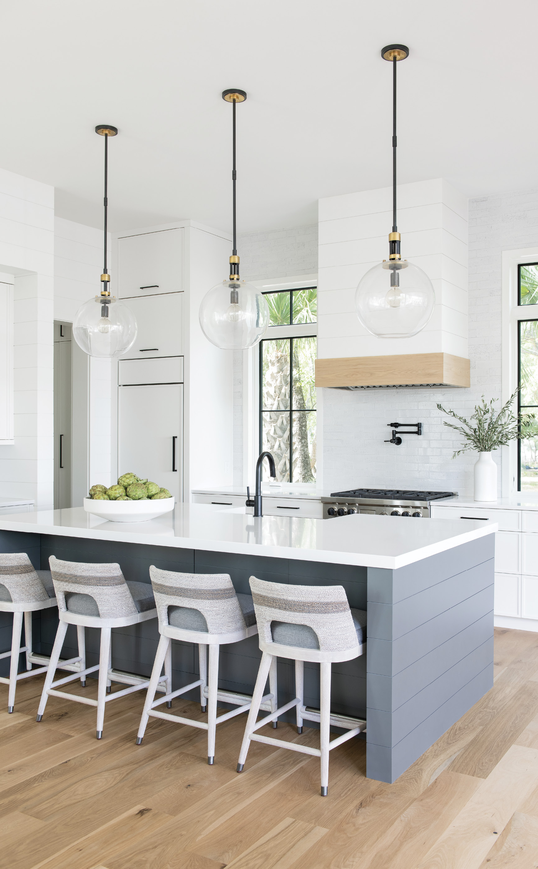 Center Stage: Four Palecek “Fritz Rope” stools provide front-row seating in the streamlined kitchen, where Frank can show off his cooking skills. The Silestone quartz-topped island incorporates a Rohl farmhouse sink and a Brizo faucet to match the pot filler above the Wolf range. The latter, set into a gorgeous Fireclay Tile backsplash, was a top priority for the home cook. “I just love my pot filler,” he says. “I use it all the time.”