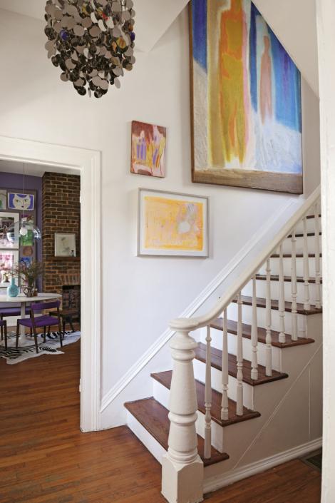 Mid-century art by P.R. McIntosh and others light the stairway with fluorescent color. The 1960s chrome disc chandelier is by Verner Panton.