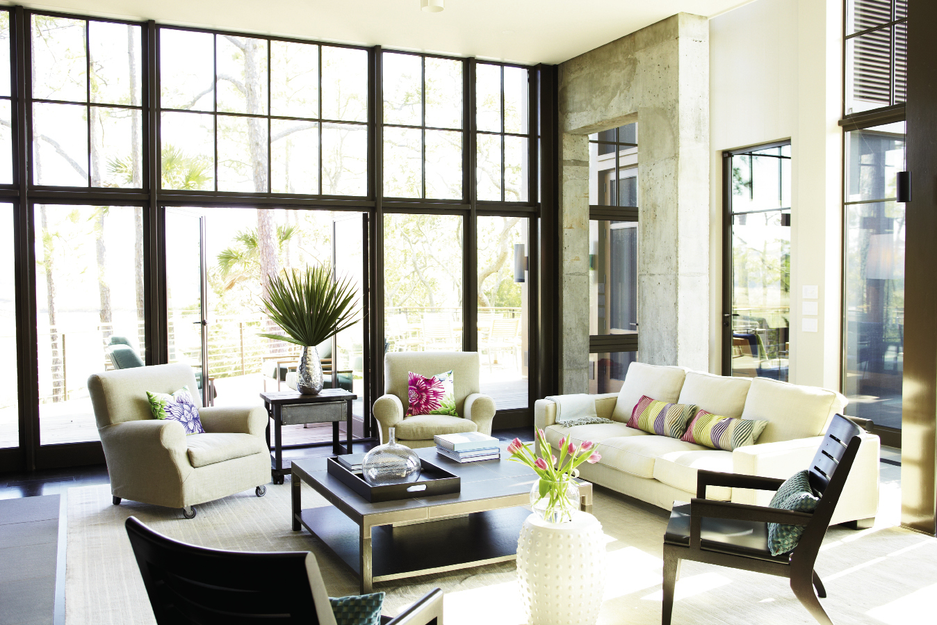 Neutral Territory: The wide-open living room is furnished simply with linen-upholstered sofa and chairs and a leather-top coffee table. It is enclosed on two sides by glass and opens to an ipé deck and screened porch.