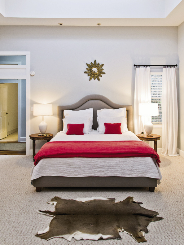 The master bedroom, furnished with a pair of lamps from Celadon, a deerskin rug from the boys’ hunting collection, and an upholstered khaki headboard from GDC.