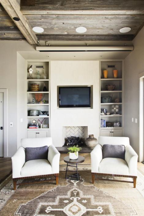 Neutral Territory: An antique Oushak rug is a natural backdrop for a pair of linen chairs from Baker Furniture. The wall flanked by bookcases is finished in Venetian plaster.