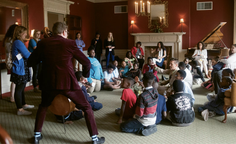 10:45 a.m. - Pre-show Pep Talk: Students and chaperones from Sanders-Clyde Elementary meet upstairs in the Dock Street’s Wadsworth Room before the morning concert. Nuttall (seated) and cellist Joshua Roman lead a quick demo, teaching the kids harmonies from Roman’s composition that will be performed. During the show, Nuttall will ask the audience to hum along, led by the students.