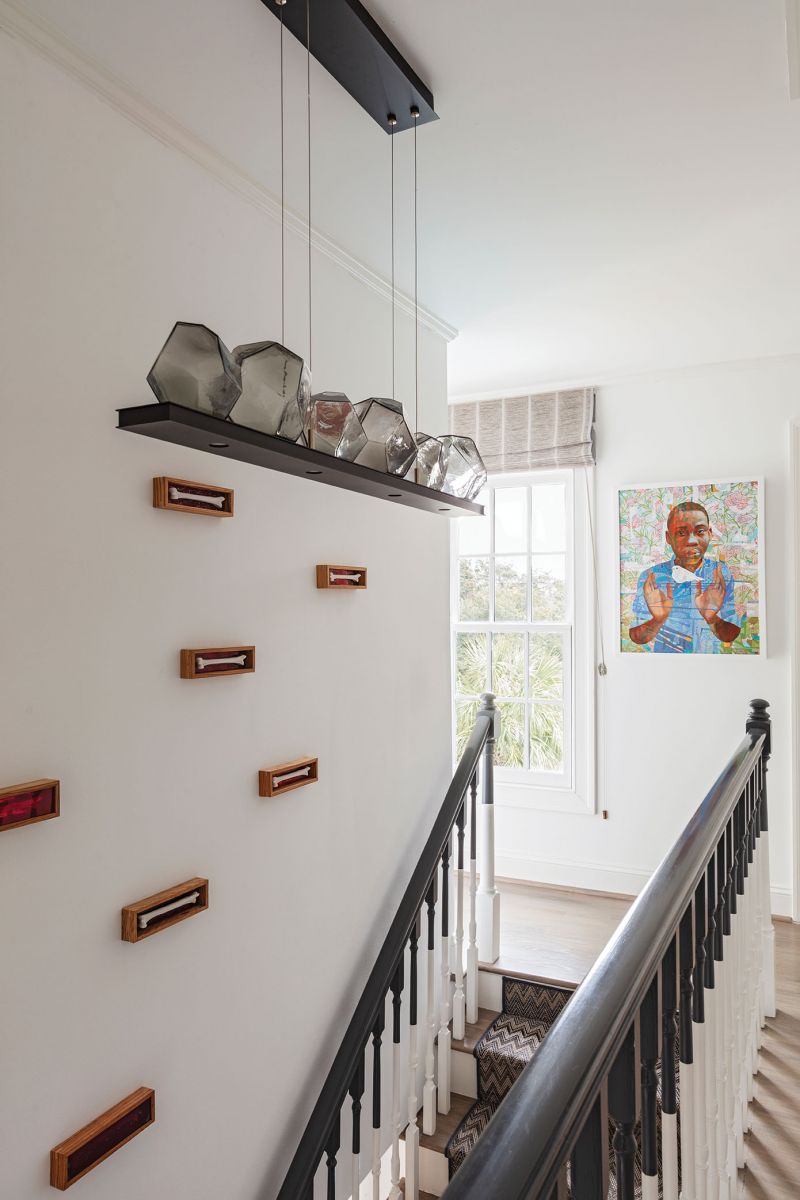 The banister, transformed into a design element with a couple gallons of paint, leads to artist Paul Hitopoulos’s Inner Elevation. This installation consists of wooden boxes painted with red nail varnish and theatrical gel, each housing a plaster bone. A Hammerton Studio chandelier accentuates the three-dimensional work, which is capped by a painting by Virginia artist Kevin Chadwick.