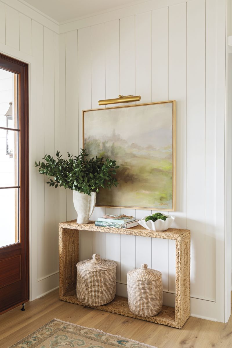 A Warm Welcome: Much to the couple’s surprise, the foyer design didn’t include a coat closet. “I thought, ‘Well, this is different,’” laughs Jamie, who, after two years of enjoying the Lowcountry’s mild winters, now gets it. Instead, an airy rattan console from GDC Home and a soothing abstract from Fritz Porter ground the space.