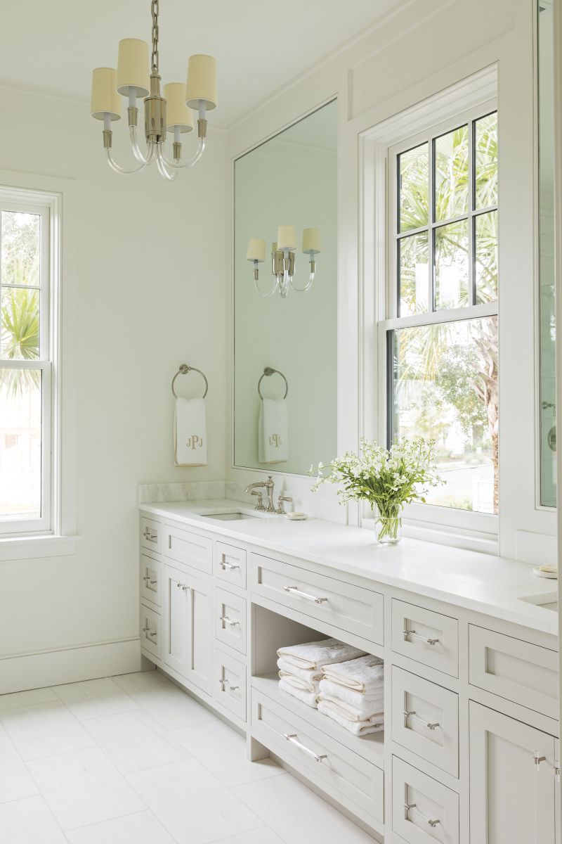 Classic Beauty: The primary bathroom—featuring Circa Lighting’s “Vivian” mini chandelier and double sconce, gold-embroidered Weezie towels, and acrylic hardware—exudes a quiet charm.