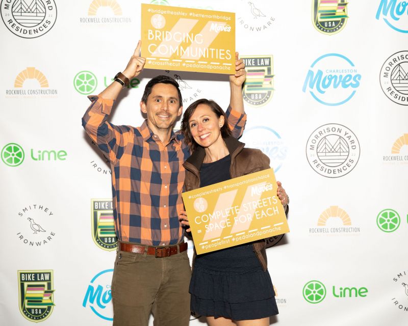 Thom Kephart and Sarah Castle pose in front of the photo wall.