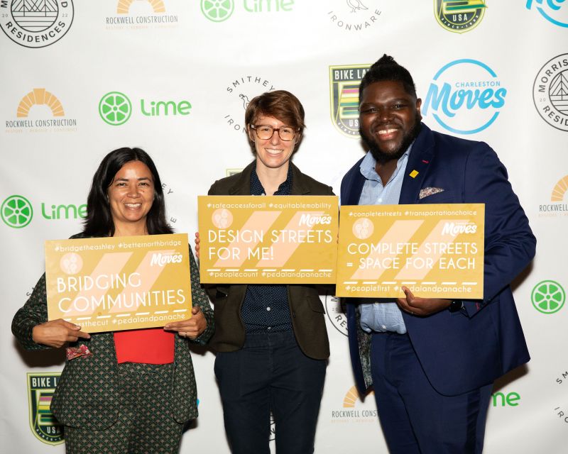 Desiree Hunter, Charleston Moves director of programming Savannah Brennan, and John Mitchell pose in front of the photo wall.