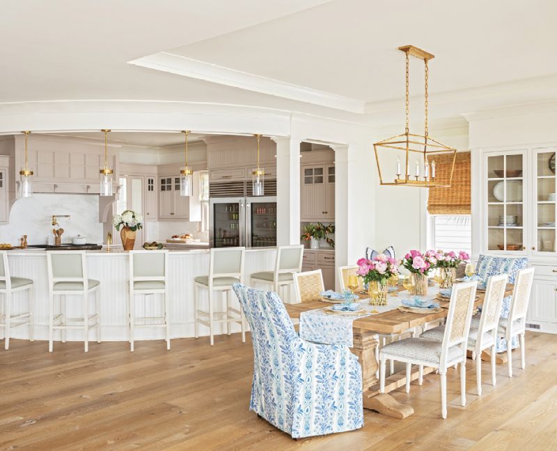 GATHER ROUND: The curved, two-tier kitchen island, original to the home, is a high-traffic area, for the boys especially. “I like to see them all lined up there just like when they were little,” says Amy, noting they had a similar island decades ago. Formerly a mix of white and dark wood, the kitchen cabinets now wear Farrow &amp; Ball’s “Elephant’s Breath,” with a hint of pink. “It’s so beautiful when you get that sunset light coming in,” says Allison. Glass and brass pendants from Circa Lighting add further warmth to the space.