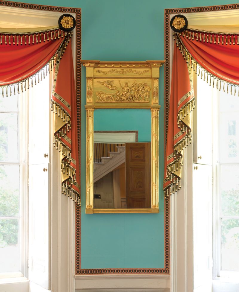 A palette of verditer blue and red enlivens the dining room of the Nathaniel Russell House. Elaborate passementerie and wallpaper trim inspired by the interlocking rings of a set of chairs original to the house further animate the room’s decor.  (Opposite) Scarlet upholstery and black-and-gold japanning accentuate the bold yet graceful form of an early 19th-century sofa in the drawing room of the Federal-period Joseph Manigault House.
