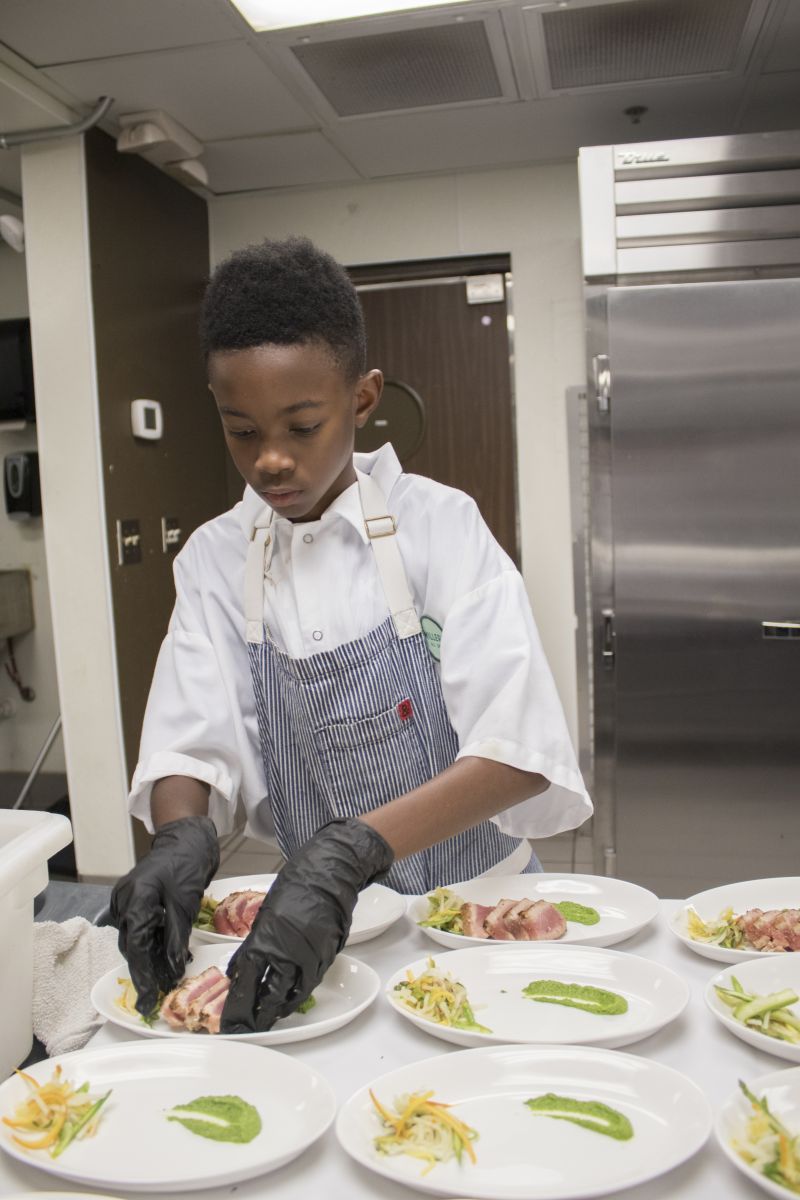 Jaylen Jones helps prepare the first course for guests.