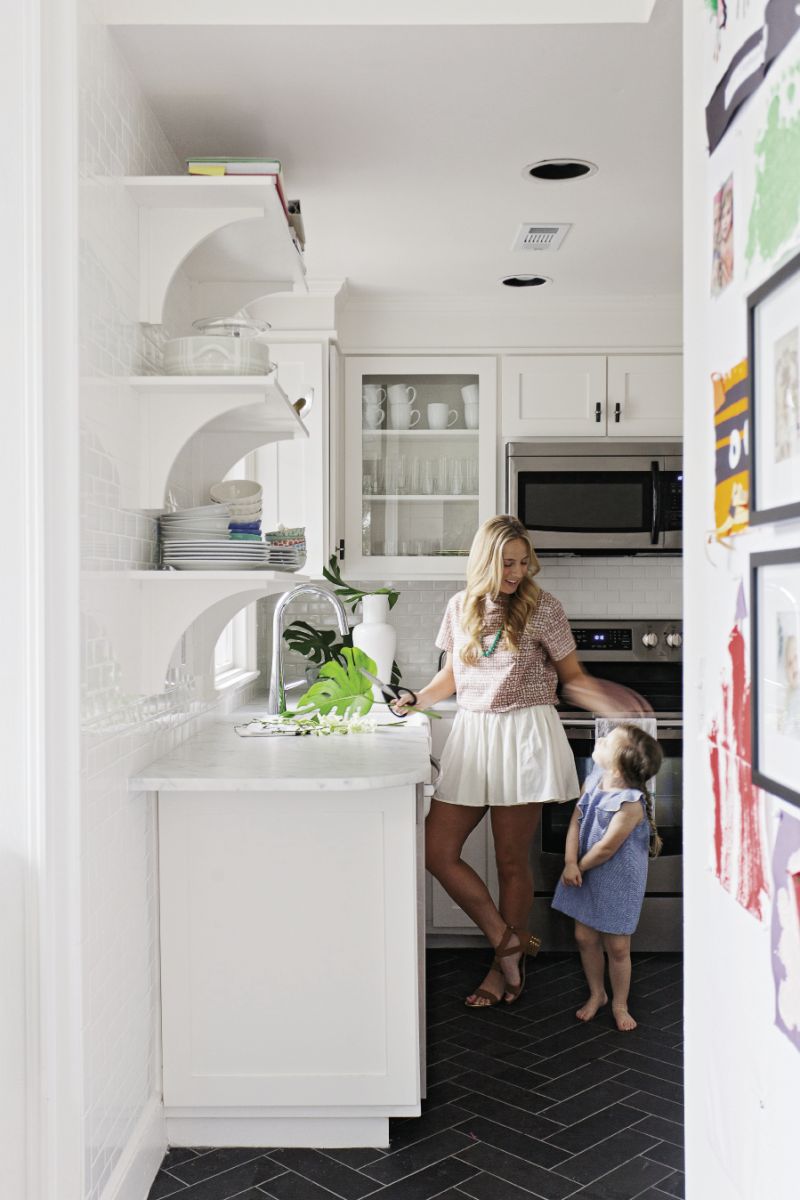 Small Serving The tiny kitchen lives large with new marble counters, a classic coat of white, and glass-front cabinets. Floor tiles in a herringbone pattern add fun contrast.