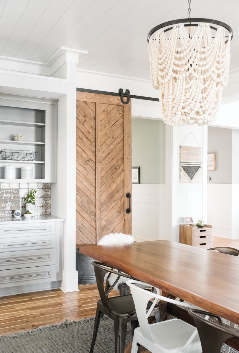 In the Mix: A wooden bead chandelier and an eclectic mix of chairs around the farmhouse table lend casual elegance to the dining area.
