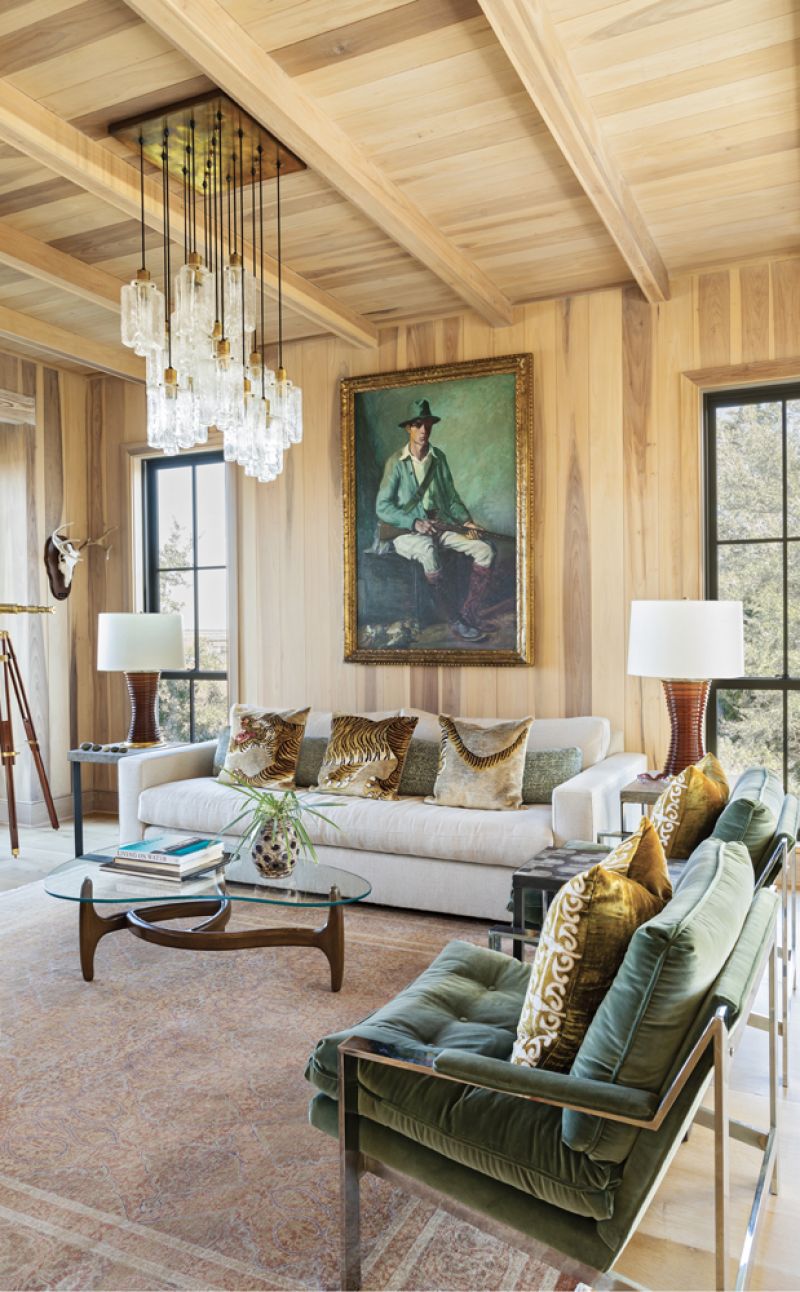 Conversation Space: The wood-paneled study is infused with warm tones. Chrome lounge chairs, upholstered in a Maharam cotton velvet, pick up on the green emanating from the dashing Hunter with Rabbits portrait by American painter Albert Edward Sterner (1936). A 1960s Kalmar light fixture with cascading, multi-tiered rectangular drops spills down to a mid-century Danish kidney coffee table, atop an antique rug.