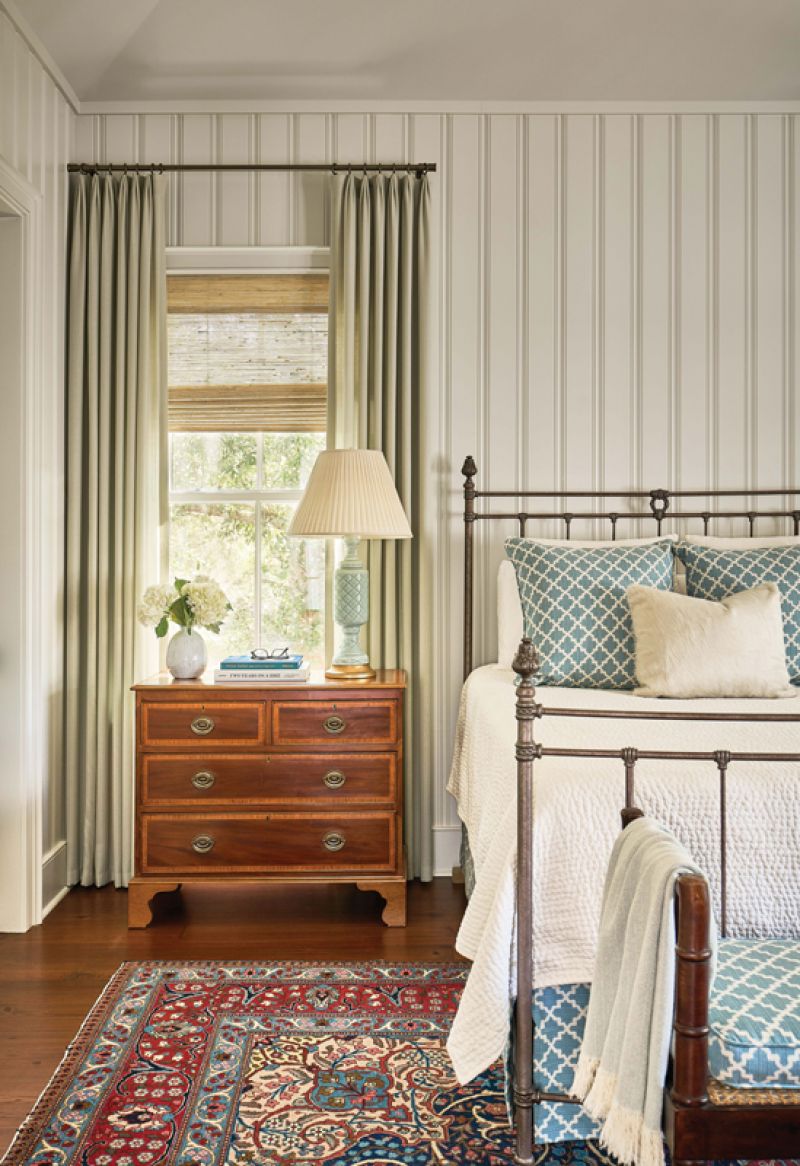 The second wing hosts the primary bedroom suite, including a walk-in closet and luxurious bathroom. The stone floor, marble wall tiles, and Sherwin Williams “Urbane Bronze” cabinet color bring sophistication to the space. An antique bed and chest from the couple’s Atlanta home sit atop a circa-1900 Persian Tabriz rug.