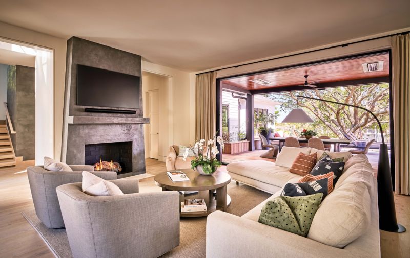 Curves &amp; Contrasts: An asymmetrical sofa in the main living space keeps the room open and allows for an easy flow. The plaster fireplace by Jess Kolar Artistic Designs contrasts beautifully with creamy walls; the reglet reveal in place of crown molding continues the clean, modern lines of the home. These contemporary elements are softened subtly by comfy chairs in soft colors from Restoration Hardware and Maiden Home.