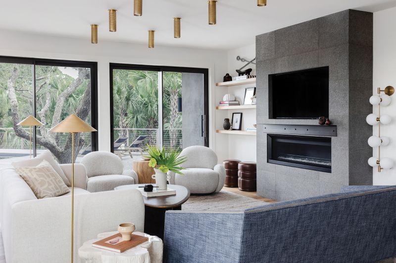 Pops of blue from the Arteriors settee and cabinets painted Farrow &amp; Ball “De Nimes” pepper the white palette where hints of brass in the light fixtures from Visual Comfort and warm woods add an organic feel. Rust-colored Maria Yee dining room chairs surround the Baker Furniture table.