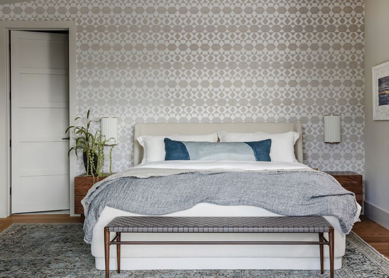The new wing encompasses the primary bedroom and bathroom suite with space for a sauna, shower, and walk-in closet. The low-slung bed from Interlude Home, accented with Phillip Jeffries patterned wallpaper, offers a luxe space to enjoy the view across the pool to the marsh.