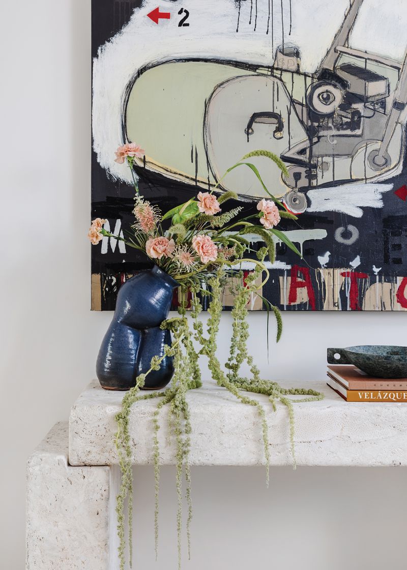 The House of Nomad design team chose Benjamin Moore “Swiss Coffee” for the walls, an ideal backdrop to showcase the couple’s art collection, including this mixed media To Grow or Mow by Australian artist Marc Renshaw. Situated above a vintage coral stone console in the entryway, it’s a playful welcome for visitors.