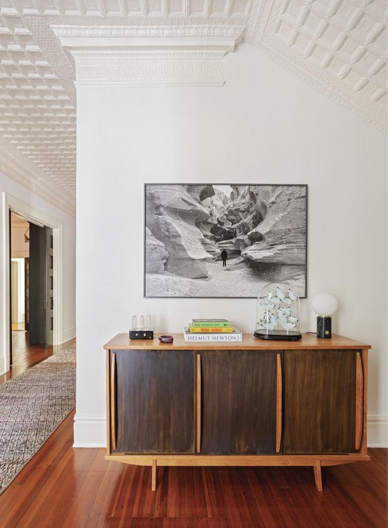 Custom-Made: For the large entryway, Sarah designed this maple wood credenza with blackened brass sliding doors built by local woodworker Scott Meara. Inspired by French architect and designer Jean Prouvé, the piece evokes a mid-century mood but fits in with the hallway’s soaring ceiling. A black-and-white photograph by Johnnie Chatman and a marble glass globe lamp from Soho Home tie together the modern yet classic feel.