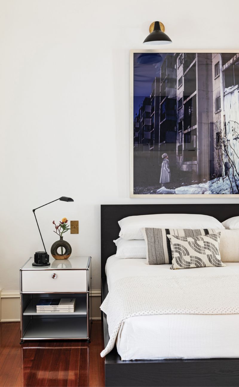 Simply Elegant: The primary bedroom suite on the second floor employs a monochromatic palette. An Ikea bed and contemporary nightstands from USM Modular Furniture sit below a large photograph by Yeondoo Jung that dominates the simple space.