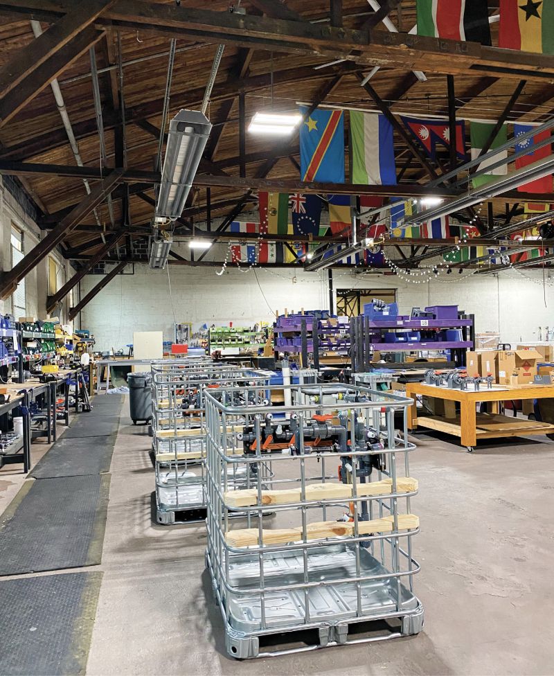 Steel cages protect the systems during transport and in the field in disaster response situations, while concrete structures house permanent systems in partner communities (represented by the flags flying in the warehouse).