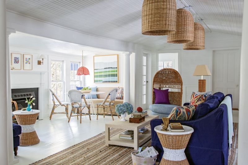 Big Imagination: For the living area, Isbell created three spaces in the former dining room. Serena and Lily wicker pendants and a slip-covered sofa delineate the main seating area, capped by a vintage hooded wicker chair from Chairish. A banquette from Ballard and bistro chairs from Serena and Lily comprise the breakfast nook.