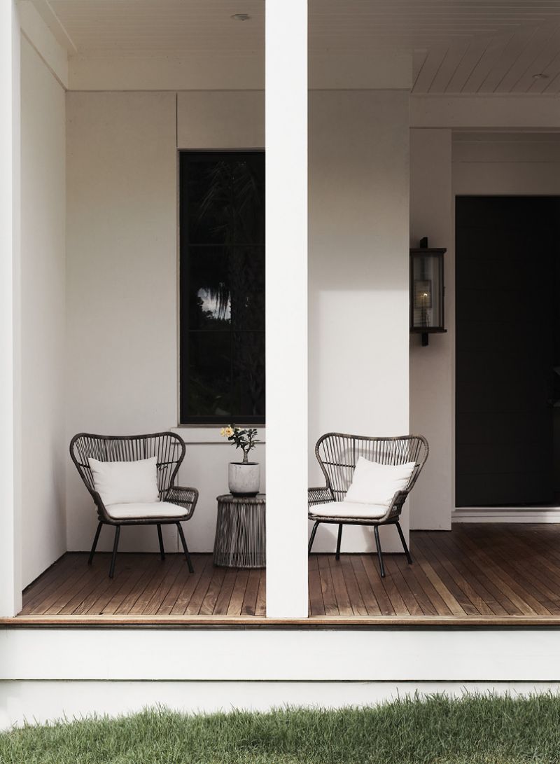 Mixed Metal: The design of the gas lanterns, crafted by Khalima Lights on Wadmalaw Island, features copper, iron, and an exposed brass backplate for a bold statement on the front porch. Black rattan chairs complete the look.