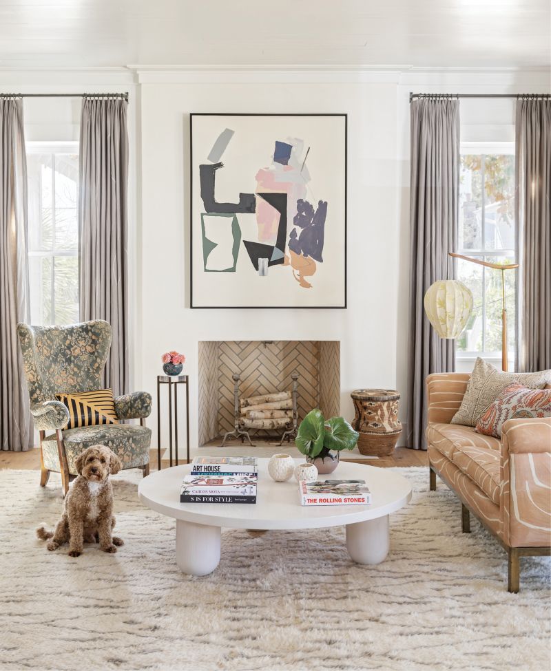 art works: When it comes to art, “Buy what you love” is Jenny’s mantra. “It doesn’t have to match your furniture, fabric, or rug. If you love it, you can put a piece of art anywhere,” says the designer. For her home decor refresh, she rearranged existing art, finding a new home for this abstract Brian Coleman piece in the living room. Centered above the fireplace, it clashes comfortably with the vintage sofa covered in the Kelly Wearstler “Graffito” fabric in “Salmon/Cream.” Pup Rowdy clearly approves.