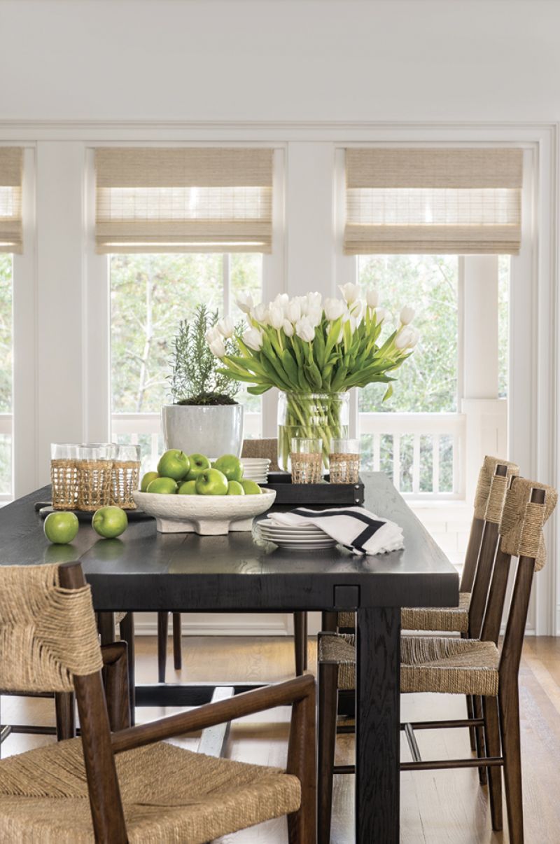 Just beyond, the dining room hosts a large Restoration Hardware table surrounded by Serena &amp; Lily woven arm and side chairs.