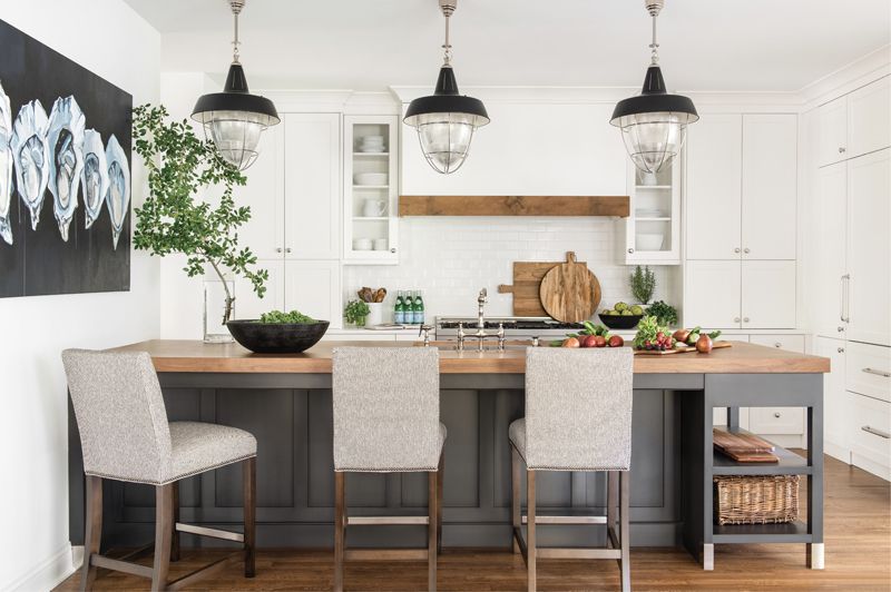 ROOMS TO GATHER: While neither consider themselves chefs, Kristin and David love to entertain, and this spacious galley kitchen overlooking a casual dining area creates an ideal flow for enjoying food and wine with friends. Three Visual Comfort “Henry Industrial Hanging Lights” from Circa Lighting and a commissioned art piece by local artist Chelsea Goer overlook the island with its a custom marine-finished walnut countertop.