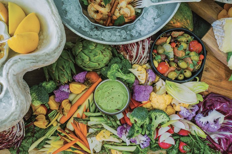 The abundant array on the snack table includes pickled shrimp, citrus olives, crudités, local oysters with cucumber mignonette, a mushroom tart, and a selection of breads and cheeses.