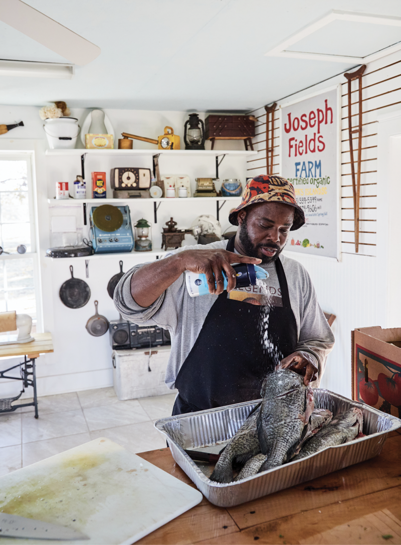 Chef BJ Dennis seasons black drum before cooking them over coals at Joseph Fields Farm on John’s Island.