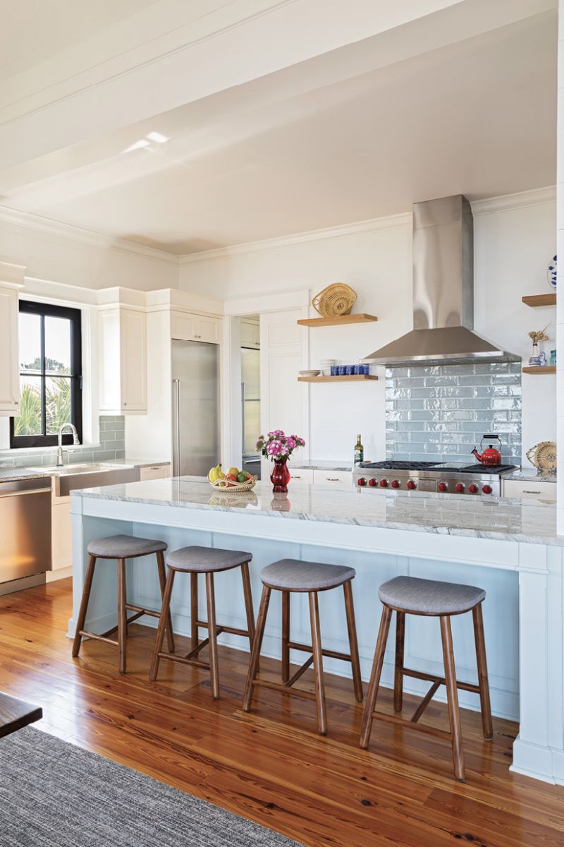 In the kitchen, the glass tile backsplash complements the pale blue kitchen island topped by a glossy quartzite counter.