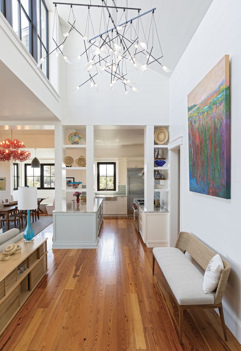 A painting by Ann Watcher depicting a marsh scene fills a large central wall where more light streams in from the rooftop deck